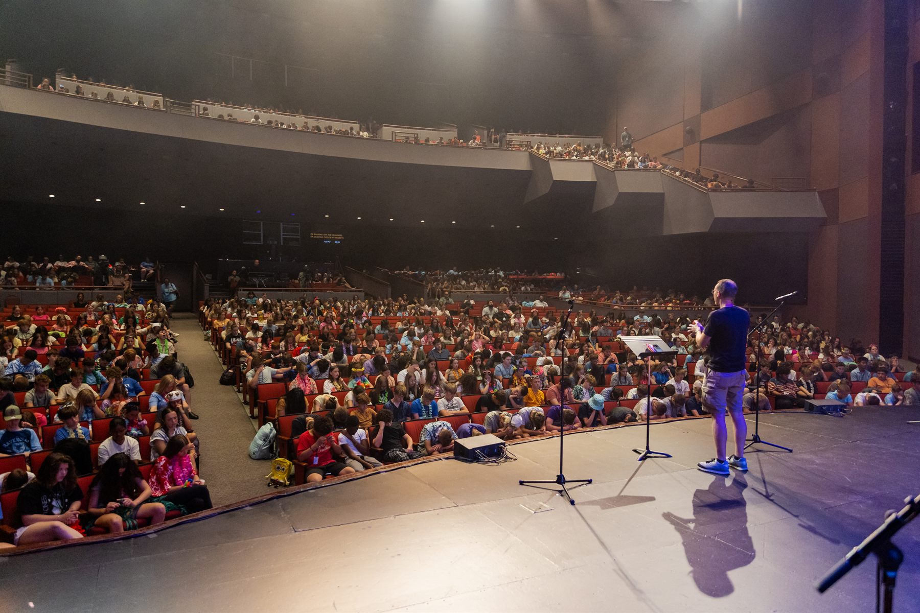 A speaker on stage in front of a full auditorium of students at Super Summer
